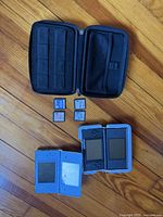 Open carrying case, two consoles, four game cartridges visible