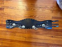 Full view of black leather kidney belt laid flat showing buckles, strap tongues, studs and conchos