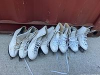 Four pairs of white figure skates lined up showing overall condition