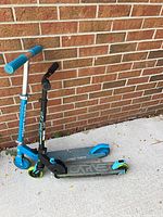 Both scooters leaning against brick wall