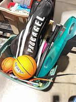 Bin showing basketball, racket covers, racquet handles and teal plastic bar