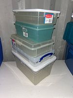 Stack of five plastic storage boxes showing varying sizes, colors, lids, and labels
