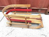 Top angled view of full wooden sled showing red side slat and metal hardware