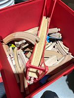 red bin filled with wooden train track pieces and bridge support