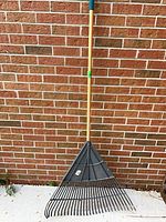 Full view of Yardworks rake leaning against brick wall