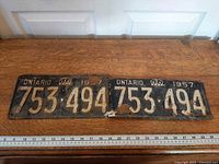 Full view of both 1957 Ontario plates side by side with ruler for scale