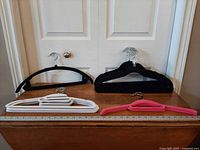 Assorted velvet hangers displayed against door, ruler for scale