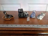 Group of five ceramic figurines with ruler for scale