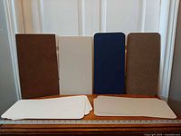 Front view of four upright matboards and stacks of additional boards showing colors and corner shapes