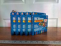 Five sealed packs standing in row showing front graphics and colour indicators