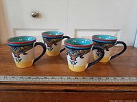 Front view of all four Zanzibar pattern mugs with ruler for scale
