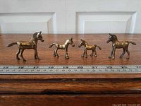 All four brass horse figurines with ruler for scale