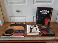 All four guitar instructional books aligned on table beside ruler for scale