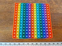 Full view of square rainbow multiplication pop-it with ruler for scale