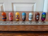 Front view of all seven Mighty Beanz in a row beside ruler