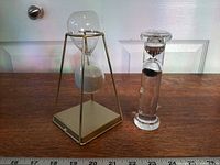 Both hourglasses side by side on wooden surface with ruler for scale