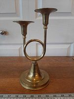 Front view of brass double French horn candlestick holder