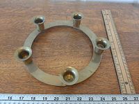 Top view showing circular brass ring with five candle sockets and ruler for scale