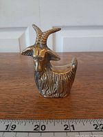 Front-left view showing full figurine, horns, and fur texture with ruler for scale