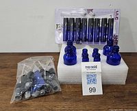 Overview showing all cobalt blue bottles, packaging of roller bottles, foam block with bottles, and bag of pump tops