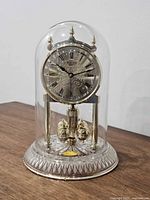 Full view of Bulova anniversary clock under glass dome on crystal base