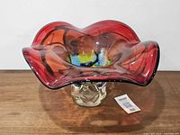 Front view of red multicolour art glass pedestal bowl on wooden surface