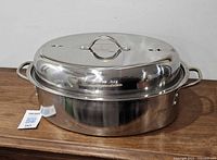 Full view of stainless steel oval roaster with lid and side handles