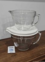 Two glass measuring cups stacked; larger Pampered Chef on bottom with lid, smaller Anchor Hocking on top