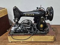 Left side view of Singer 99K sewing machine on base with cords