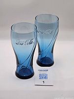 Front angled view of both blue Coca-Cola glasses