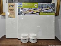 Front view of two wrapped canvases and two sealed Golden gel mediums