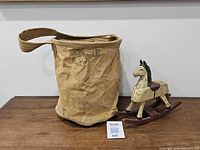 Canvas water bucket and wooden rocking horse side by side