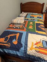 Overall view of comforter on bed displaying vehicle graphics and folded sheets on top