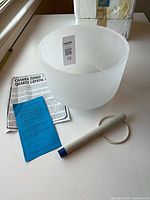 Top view of singing bowl with mallet, O-ring, care guide and blue card