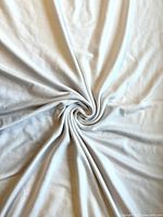 Close-up of white tubular knit fabric spread out showing texture and drape