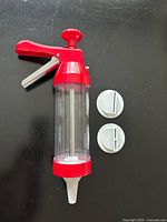 Overall view of meat extruder gun with two nozzle discs beside it