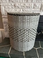 Front view of grey woven synthetic wicker hamper with lid