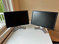 Two Dell monitors side by side on table