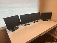 Four monitors arranged side by side on table
