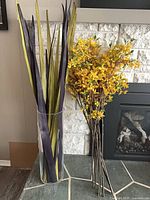 Overall view of glass vase with leaf stems and separate forsythia branches