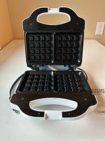 Waffle maker open showing dual square non-stick plates