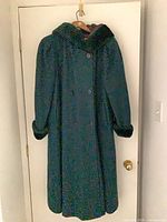 Front view of full-length dark green double-breasted coat with faux-fur trimmed hood and cuffs