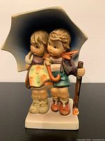 Front view of Goebel Hummel Stormy Weather figurine showing two children under umbrella