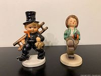 Front view of both figurines side by side on black surface