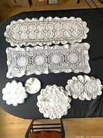 Assorted crocheted runners and round doilies on black surface