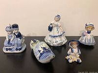 Group shot of five visible blue-white figurines and clog