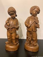 Front view of both wooden child musician figurines on bases