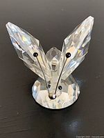 Front view of faceted crystal butterfly on base showing metal antennae and round pedestal