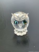 Front view of Swarovski crystal owl showing faceted body and green eyes