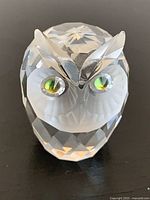 Front view showing owl face, green eyes, faceted body